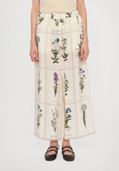 Weite Hosen aus cremefarbenem Stoff mit botanischen Drucken in Grün und Lila. Elastischer Bund, glatte Textur und entspannter Sitz.