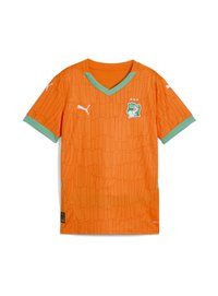 Oranžový fotbalový dres s texturovaným vzorem, V-výstřihem, zelenými akcenty na rukávech a klubovým emblémem s vyobrazením siluety a hvězd.