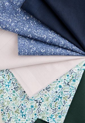 Különféle szövetminták kék, rózsaszín és zöld színekben, virágmintákkal és egyszínűek, legyező alakban rétegzett elrendezésben egy sík felületen.