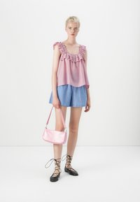 Roze gerimpelde tanktop, blauwe gestreepte shorts, roze handtas met krokodillenpatroon en zwarte veterschoenen. Eenvoudige, casual zomeroutfit.
