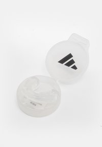 Transparent tandskydd i ett klart cirkulärt fodral med en svart logotyp. Tandbeskyddet är utformat för tandvårdsskydd och har släta kanter.