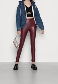 Jeansowa kurtka z kapturem, czarny krótki top z wycięciem, burgundowe legginsy z ekologicznej skóry, torebka w kratę, czarne buty na platformie.