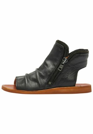 Zwarte leren open-toe sandalen met een gekreukelde textuur en zijritsen. Voorzien van een platte houten zool. Minimalistisch ontwerp met een unieke vorm.