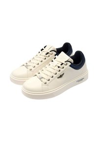 Sneakers bianchi in pelle con tallone blu navy, punta rotonda e suola piatta. Presentano occhielli in metallo e branding di lato. Dettagli texturizzati.