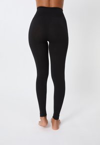 Leggings noir taille haute en matériau extensible, design ajusté, texture lisse, longueur cheville avec une taille sans couture.
