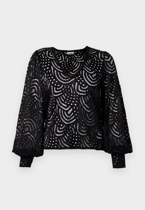 Pull en dentelle noire avec un col en V, des manches longues et un motif découpé complexe comportant des lignes courbes et des points, avec des manches côtelées.