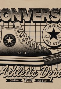 Ασπρόμαυρο σχέδιο ενός αθλητικού παπουτσιού Converse με υφή, που απεικονίζει ένα λογότυπο αστεριού και τις λέξεις «Athletic Dept» σε μπεζ φόντο.
