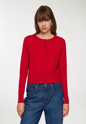 Cardigan rosso con scollo rotondo, maniche lunghe e chiusura con bottoni. Presenta un orlo a coste e una texture liscia. Abbinato a jeans blu.