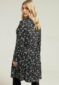 Czarna sukienka w kwiaty z długimi rękawami, falbaniastym dołem i dopasowanym gorsetem, zdobiona białymi i jasnoróżowymi wzorami kwiatowymi. Gładka tekstura materiału.