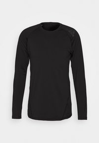 Svart långärmad träningsskjorta i mjukt, lättviktsmaterial. Har raglanärmar och subtil logotypdetalj på axeln.