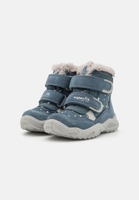 Blaue Wildleder-Kinderstiefel mit einem Fellkragen, weißen Pünktchen, zwei Klettverschlüssen und einer strukturierten grauen Gummisohle.