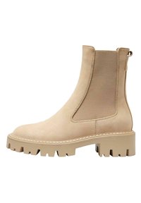 Bottines beiges avec une finition en suède lisse, des panneaux latéraux élastiques et une semelle crantée épaisse pour une traction optimale. Présente un détail de couture décoratif.