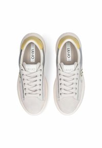 Baskets grises et blanches à texture lisse, avec des accents jaunes et un logo. Elles sont dotées de lacets traditionnels et d'un design à bout arrondi.