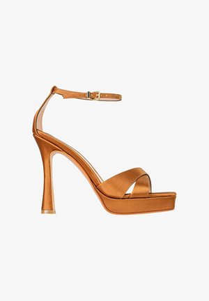 Sandalo con tacco alto con finitura satinata bronzo lucido, suola platform, cinturini incrociati anteriori e cinturino regolabile alla caviglia con fibbia dorata.