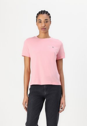 Lichtroze katoenen t-shirt met een ronde hals. Beschikt over een klein bedrukt logo op de borst. Korte mouwen, relaxte pasvorm, soepele textuur.
