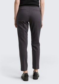Gray trousers with a slim fit, featuring two back pockets and a smooth texture. Paired with black platform shoes, visible at the ankles.