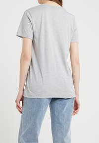 Grå bomullst-shirt med kort ärm, rund hals och avslappnad passform, sedd bakifrån. Strukturerad tyg med en slät yta.