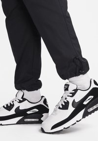 Tenisky Nike Air Max v černobílé, které mají síťovinu a syntetické materiály, polstrovaný límec a viditelnou vzduchovou jednotku v podrážce.