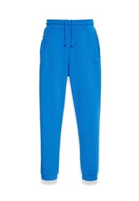 Blaue Sweatpants aus weichem Stoff, mit einem Kordelzugbund, Seitentaschen und schmal zulaufenden Bündchen. Glatte Textur mit minimalem Branding.