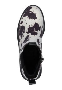 Bottines à imprimé vache noir et blanc en feutre, avec un bout rond, une fermeture éclair sur le côté et une semelle en caoutchouc noire. Intérieur doublé de matériel doux.