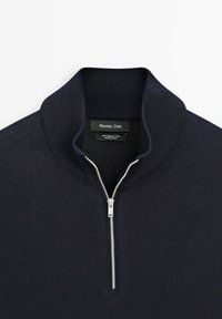 Marineblauwe merinowollen pullover met een hoge kraag en een zilveren rits. Beschikt over een zachte textuur en een klassiek, aansluitend ontwerp.