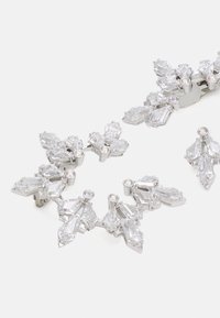Pendientes de cristal claro con un diseño floral que presenta cortes marquesa y redondos, enmarcados en acentos metálicos de tono plateado. Acabado brillante.