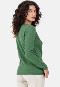 Pull vert à manches longues en matière douce, avec une coupe ajustée et des poignets côtelés. Le dos présente une texture lisse et des lignes simples.