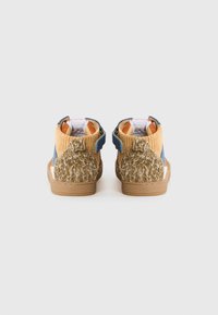 Chaussures montantes pour enfants en tissu velours côtelé bleu et beige, avec des empiècements en cuir texturé marron au niveau du talon et des semelles en caoutchouc, vues de dos sur un fond blanc.
