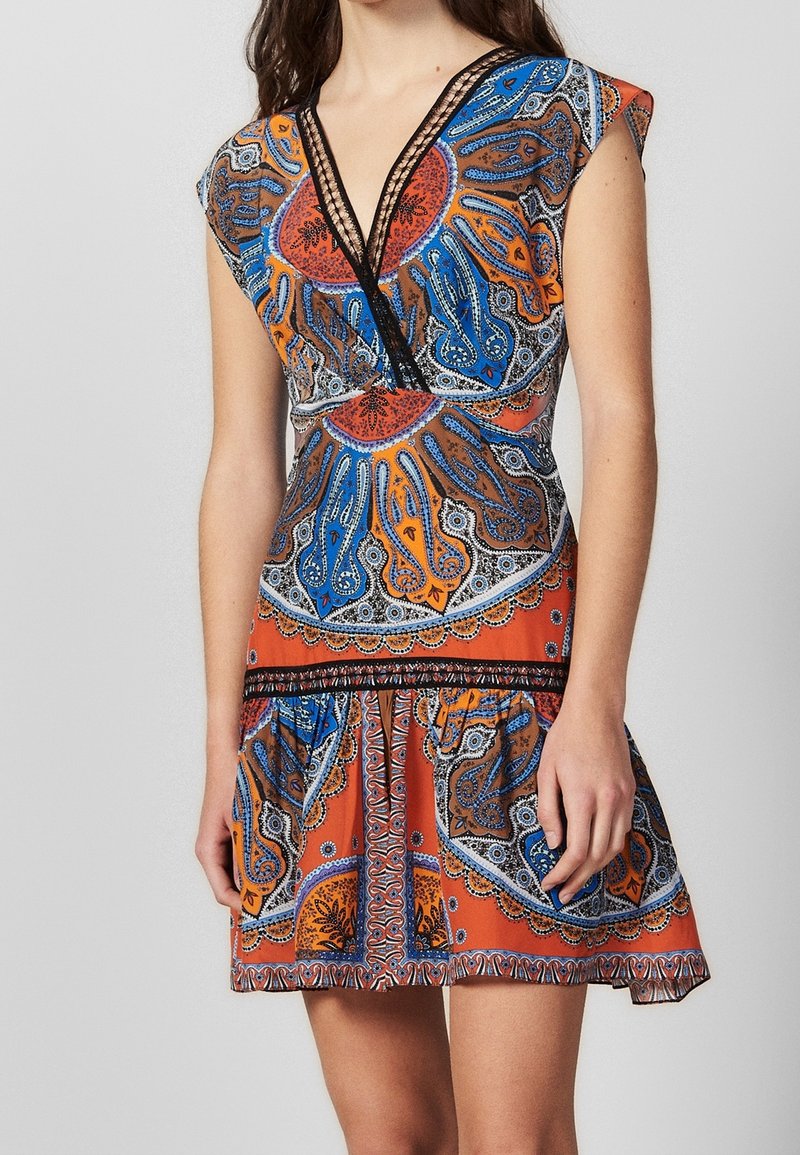 Robe à col en V avec manches courtes volantées, motif paisley en orange, bleu et noir ; présente une bordure en dentelle et un détail de jupe à volants. Fabriquée en tissu léger.