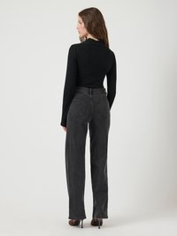 Svart ribbet langermet topp kombinert med høytlivede, rette mørke grå kordfløyelsbukser. Hælene fremhever outfitens lengde.