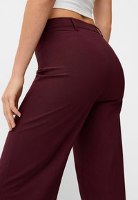 Burgundy skräddarsydda byxor med en slät yta, vid ben-design och medelhög midja, med diskreta bakfickor och bälteshällor.