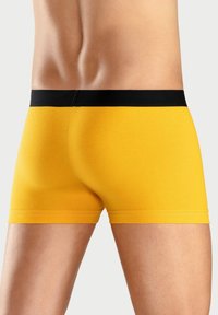 Yellow boxer shorts with a black waistband, featuring a fitted design and smooth texture, displayed from a rear perspective.