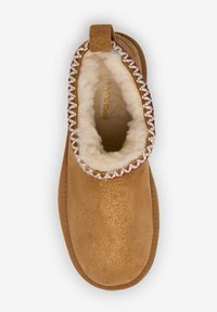 Bottine en suède marron avec une doublure en fourrure douce, à bout rond et à couture décorative autour de la cheville, dotée d'une boucle en tissu pour un enfilage facile.