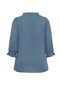 Light blue blouse with three-quarter puff sleeves, ruffled neckline, and subtle texture. Features gathered cuffs and a slightly loose fit.