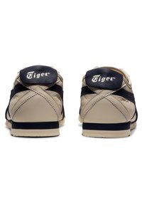 Beige sneakers with dark blue accents, textured leather material, round toe, and prominent "Tiger" logo on the heel.