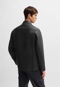 Black leather jacket with a structured design, featuring a classic collar and buttoned cuffs. Smooth texture, tailored fit.