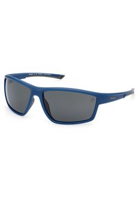 Gafas de sol de plástico azul con lentes grises, diseño angular y acabado mate. Presenta un logo plateado en la patilla. Estilo ligero y moderno.