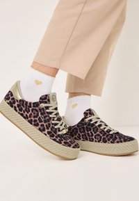 Sneakers na platformie w leopardzi wzór z teksturowaną juteową podeszwą, jasnoszarymi akcentami i szarymi sznurówkami. Połączone z białymi skarpetkami z złotym sercem.