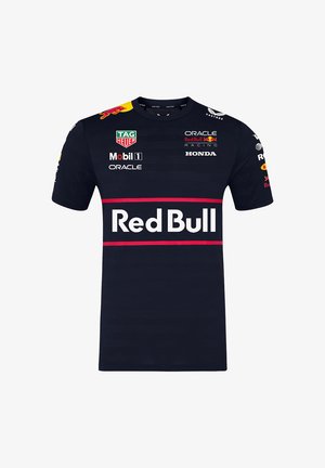 Granatowa koszulka z krótkim rękawem, z logo Red Bull, logotypami sponsorów i wyraźnym czerwonym poziomym paskiem z napisem "Red Bull".