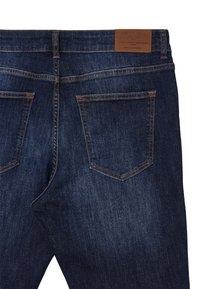 Jeans in denim blu scuro con una texture liscia, due tasche posteriori di forma classica e un'etichetta in pelle beige sulla vita.