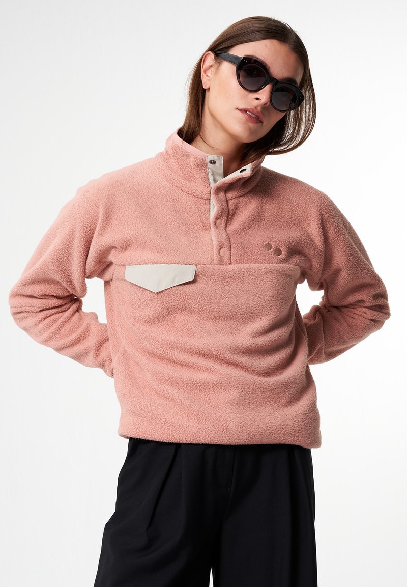 Hellrosa Fleece-Pullover mit hohem Kragen, knöpfbarer Leiste und kontrastierendem beigen Brusttasche. Weicher Stoff, lässige Passform.