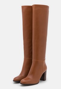 Brown leather knee-high boots with a rounded toe and a chunky wooden heel. Smooth texture and minimal stitching detail.