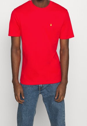 Czerwona bawełniana koszulka z okrągłym dekoltem i krótkimi rękawami, z małym żółtym logo na piersi. Miękka w dotyku, o standardowym kroju.