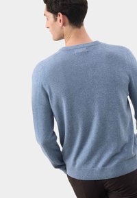 Jasnoniebieski sweter z miękkiego materiału, z okrągłym dekoltem i prążkowanymi mankietami. Gładka faktura, dopasowany krój i prosty design.