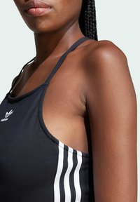 Black athletic tank top with white three-stripe design on the side. Made from smooth fabric, featuring a round neckline and thin straps.