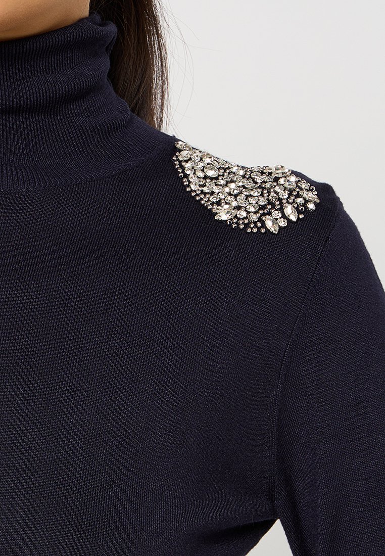 Maglione a collo alto navy in un design aderente, con un accento sulle spalle di grandi strass trasparenti decorativi disposti a grappolo.