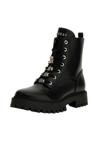 Stivale da combattimento in pelle nera con suola spessa a rilievo, decorato con charm argentati sui lacci neri e logo "GUESS" sulla linguetta.