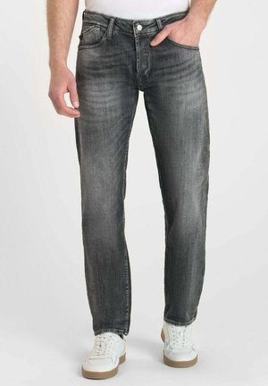 Jean en denim gris avec une coupe droite, design à cinq poches, finition délavée et fermeture à bouton en métal, associés à des baskets blanches.