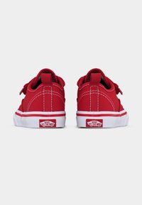 Paire de baskets Vans rouges vues de dos, montrant des semelles blanches avec des logos rouges "Off The Wall" et des détails de coutures blanches.