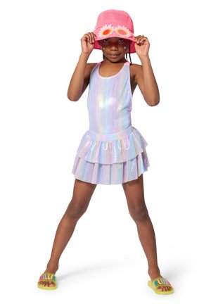 Costume intero iridescente con gonna a strati, abbinato a un cappello a secchiello rosa con dettagli floreali e sandali gialli con lettere multicolore.